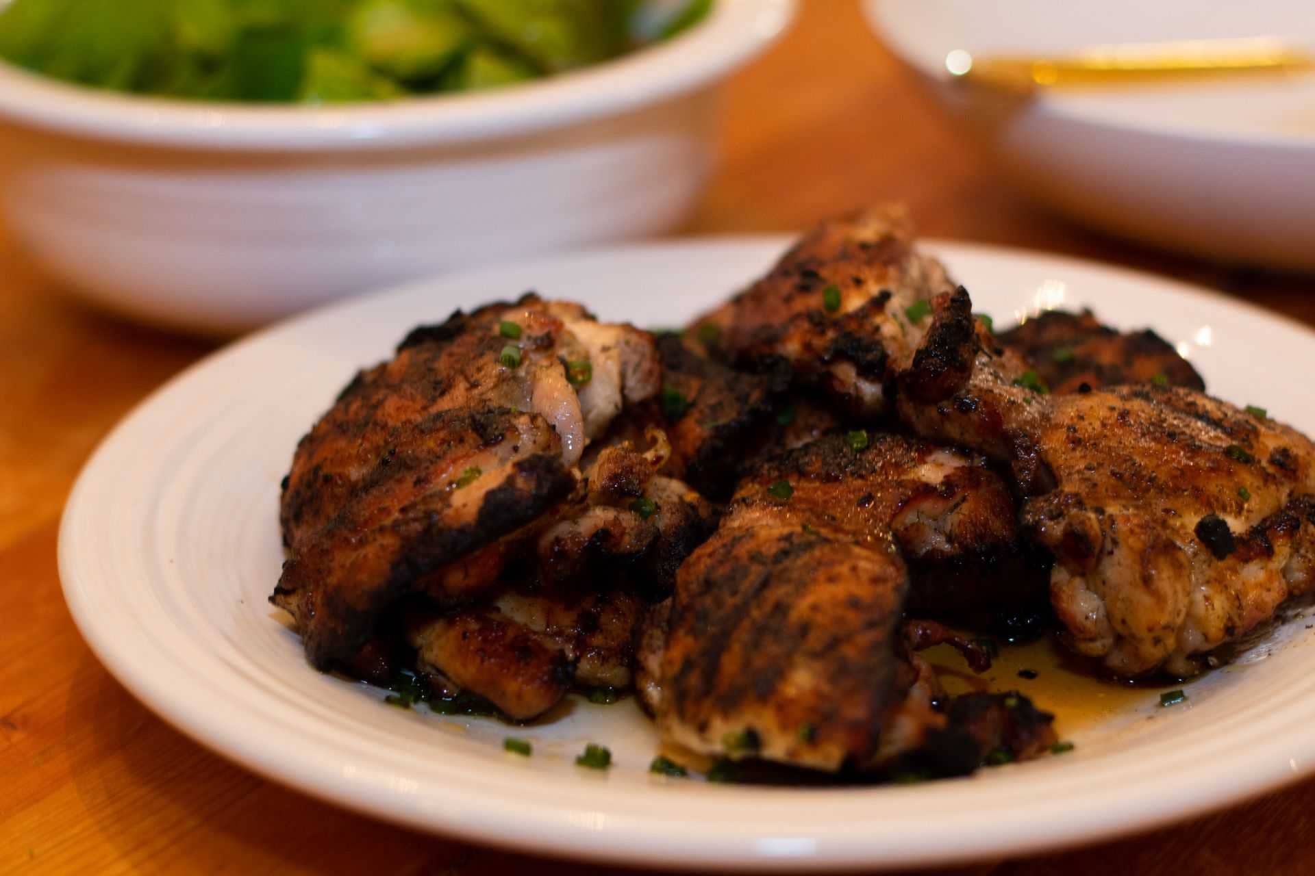 grilled chicken thighs on a plate seasoned with lemon and olive oil