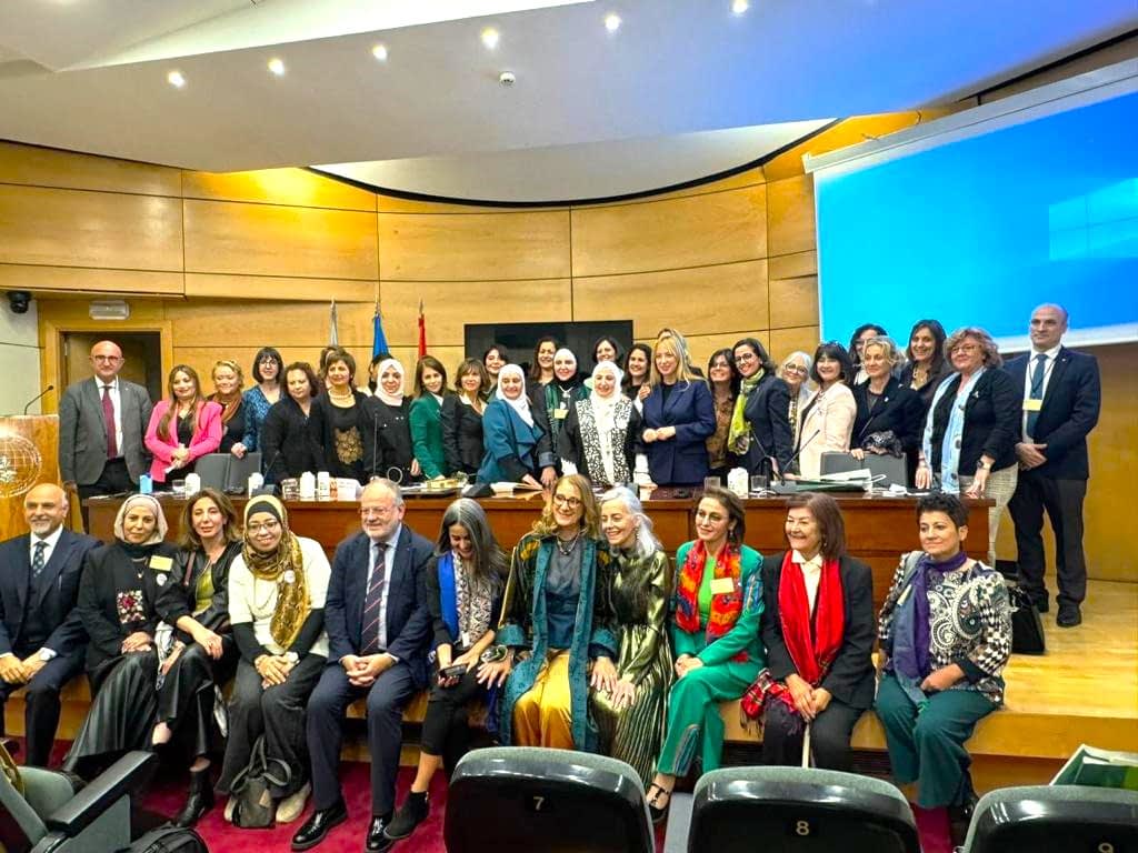 Un grupo de mujeres y hombres posando para una fotografía en un evento de conferencia en un entorno formal. Olive Oil Times