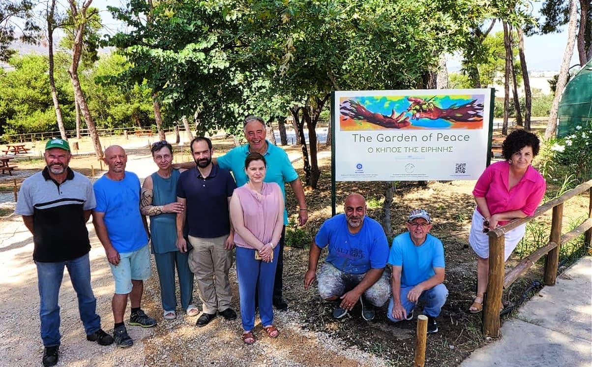 A group of nine individuals posing in front of a sign that reads 'The Garden of Peace'. - Olive Oil Times