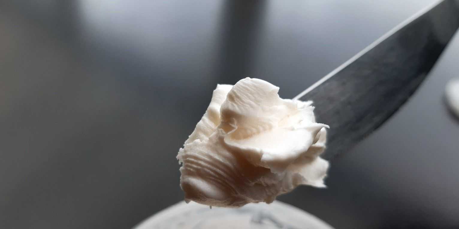 Nahaufnahme eines Messers mit einem Klecks cremeweißer Substanz darauf. - Olive Oil Times