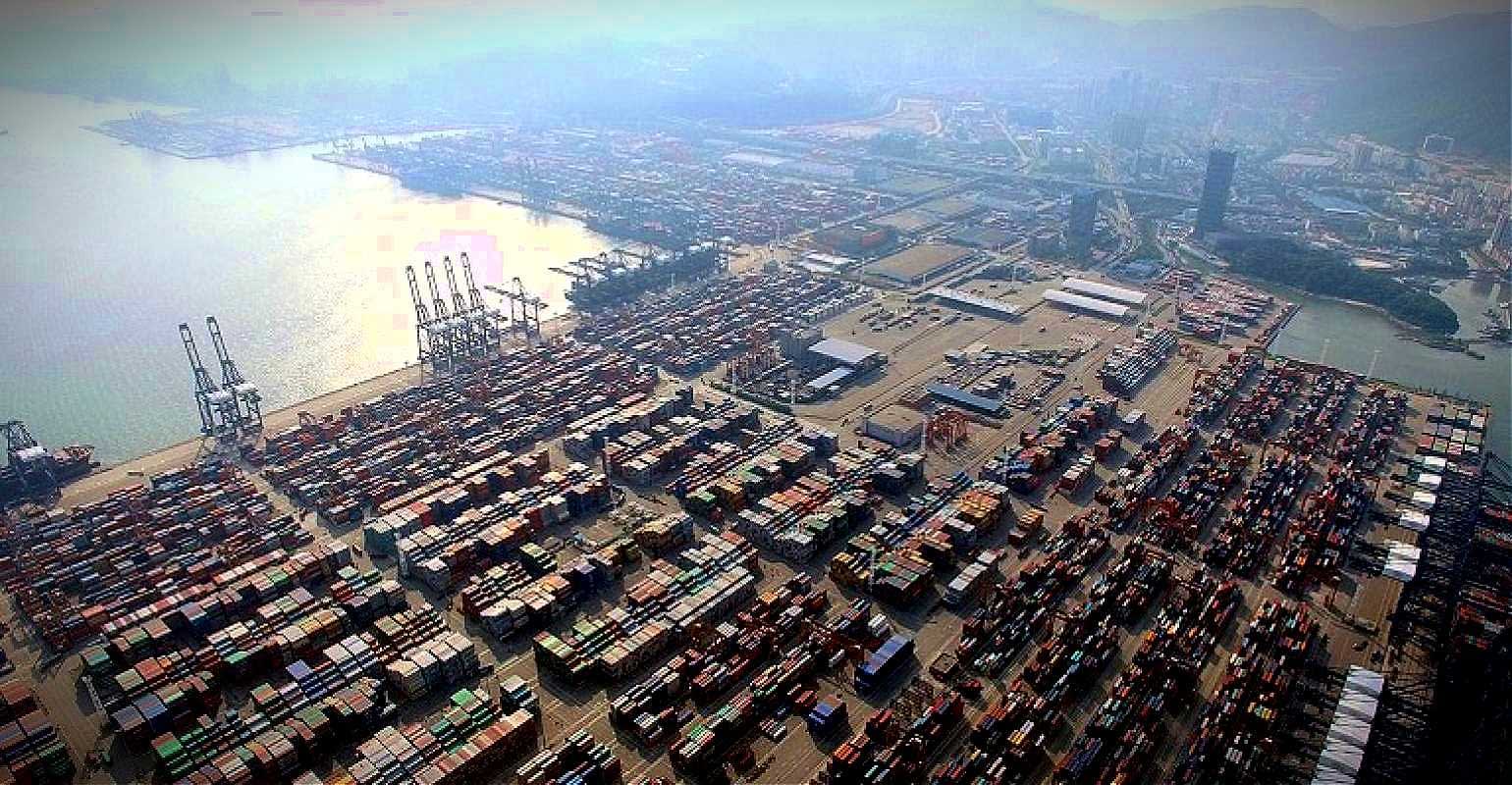 Aerial view of a busy container port with numerous shipping containers stacked. - Olive Oil Times