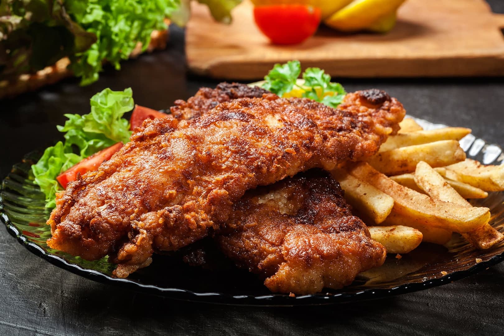 Plate of fried chicken served with French fries and a side of salad. - Olive Oil Times