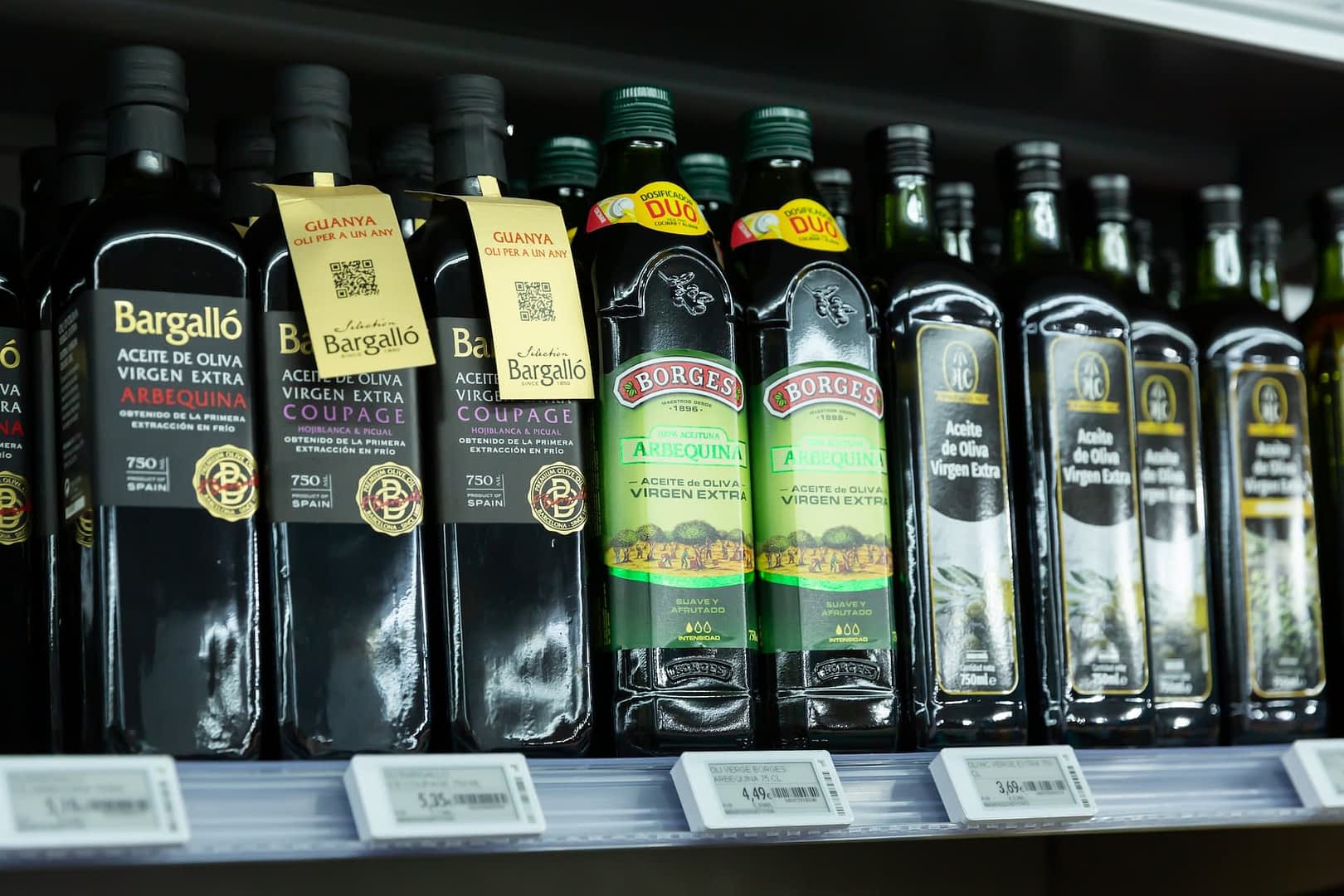 Различные бутылки оливкового масла первого отжима на полке супермаркета. Olive Oil Times
