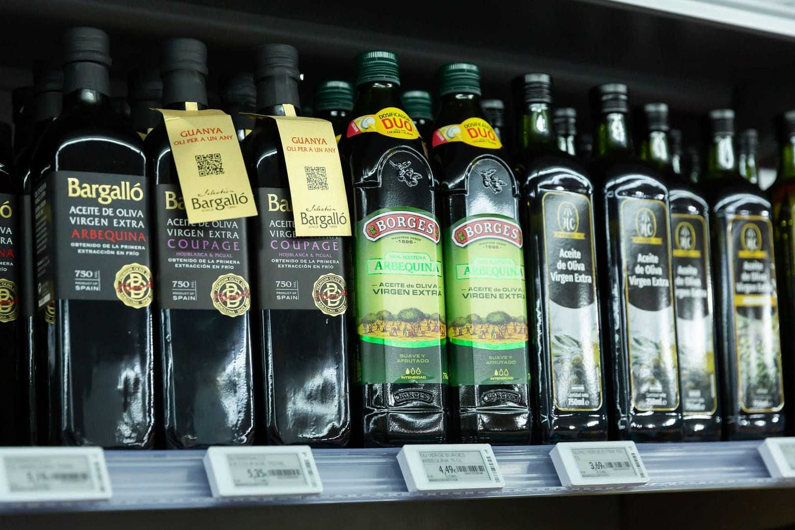 Various bottles of extra virgin olive oil displayed on a store shelf with labels and branding. - Olive Oil Times