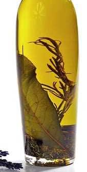 Bottle of infused olive oil containing herbs and leaves submerged in oil. - Olive Oil Times