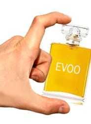 Hand holding a small glass bottle labeled 'EVOO' containing yellow liquid. - Olive Oil Times