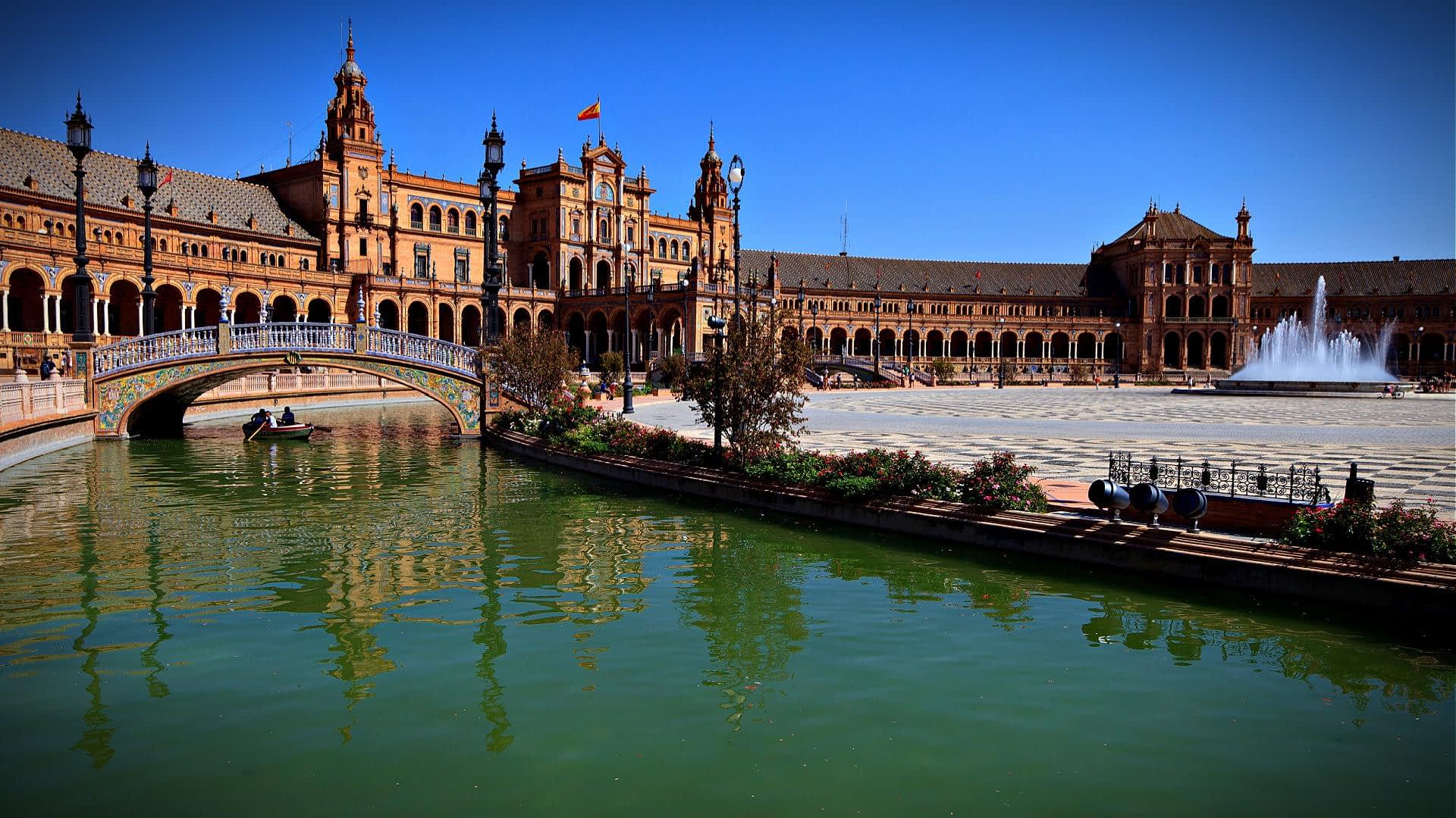 Plaza de España de Sevilla con un canal de agua y estructuras arquitectónicas al fondo. - Olive Oil Times
