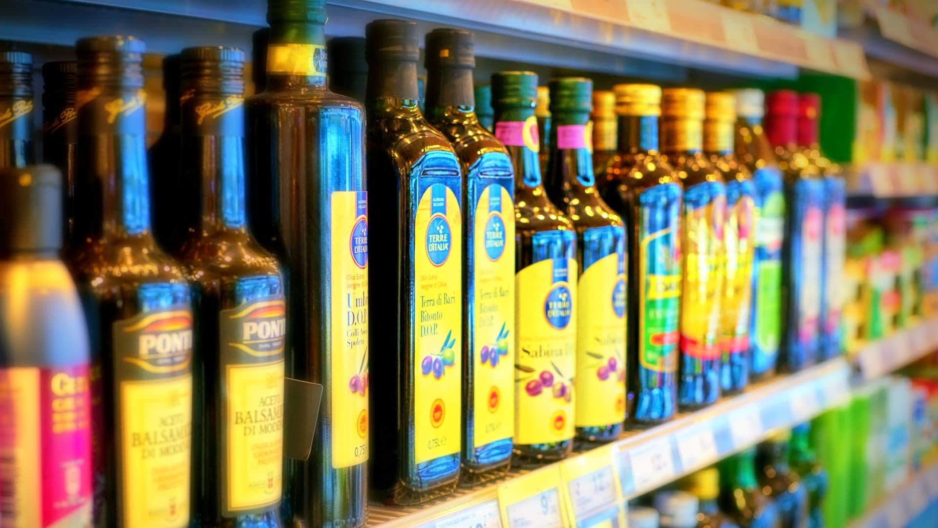 Diverse bottiglie di olio d'oliva esposte sullo scaffale di un supermercato. Olive Oil Times