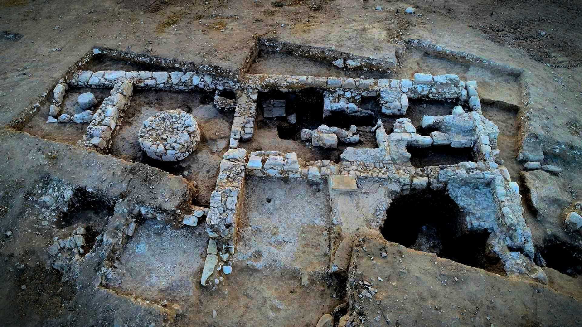 Luftaufnahme einer archäologischen Stätte mit Steinstrukturen und Ausgrabungsflächen. – Olive Oil Times