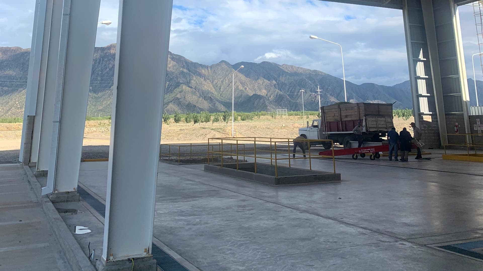 Un camion garé dans une zone de chargement avec des montagnes visibles en arrière-plan. - Olive Oil Times