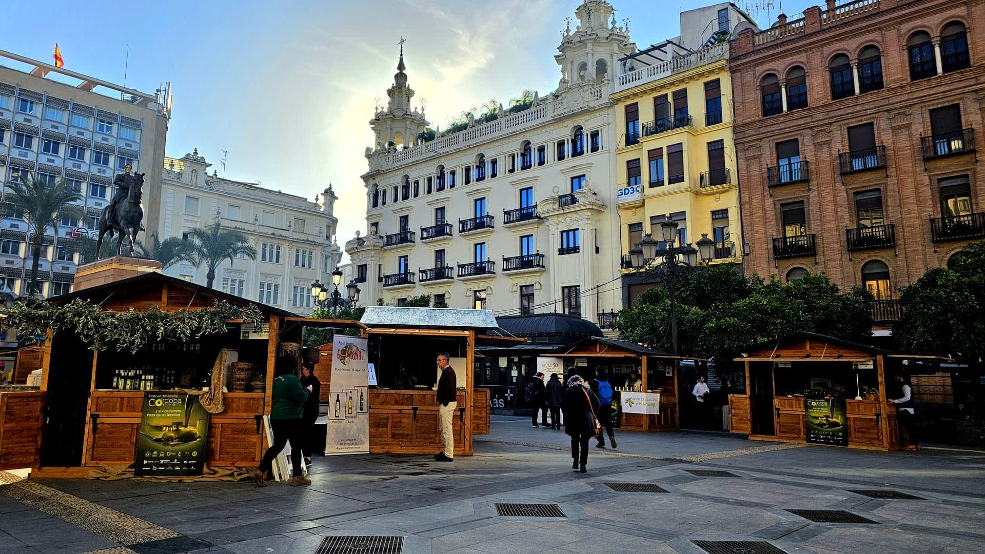 Drveni štandovi na tržnici postavljeni na gradskom trgu sa zgradama u pozadini. - Olive Oil Times