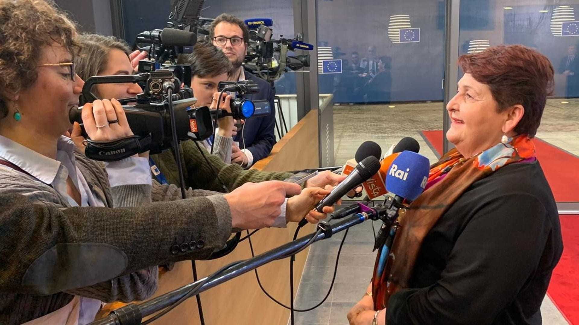 A woman speaking to reporters while being filmed by multiple cameras in a press setting. - Olive Oil Times