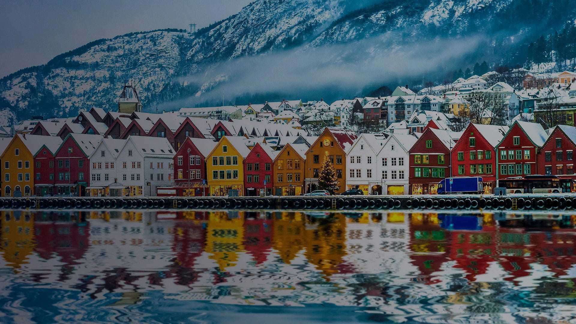 Row of colorful waterfront houses reflecting in the water in Bergen, Norway during winter. - Olive Oil Times