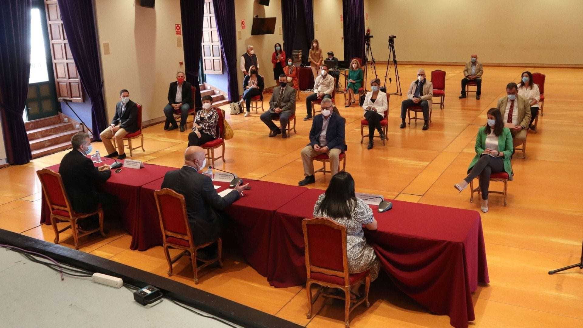 A group of people seated in a conference room during a meeting with a table in the foreground. - Olive Oil Times