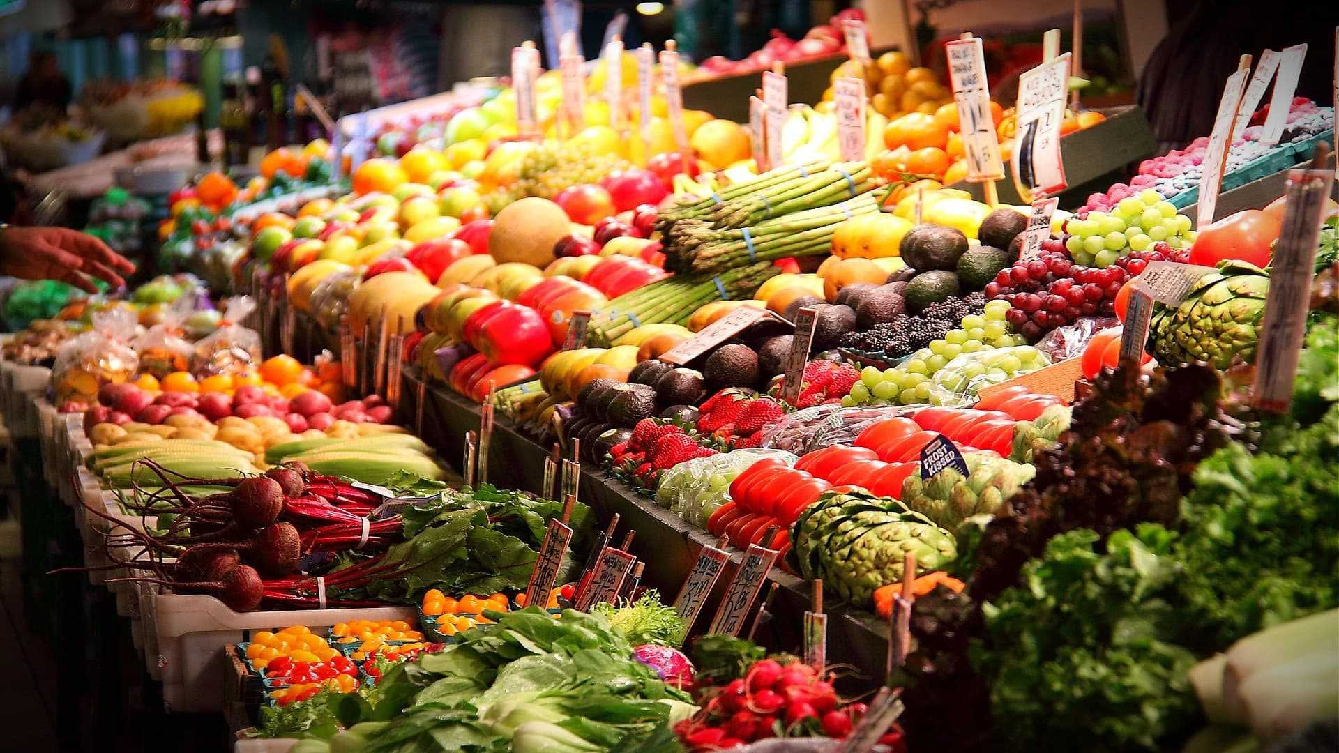 Colorful display of fresh fruits and vegetables arranged at a market stall. - Olive Oil Times