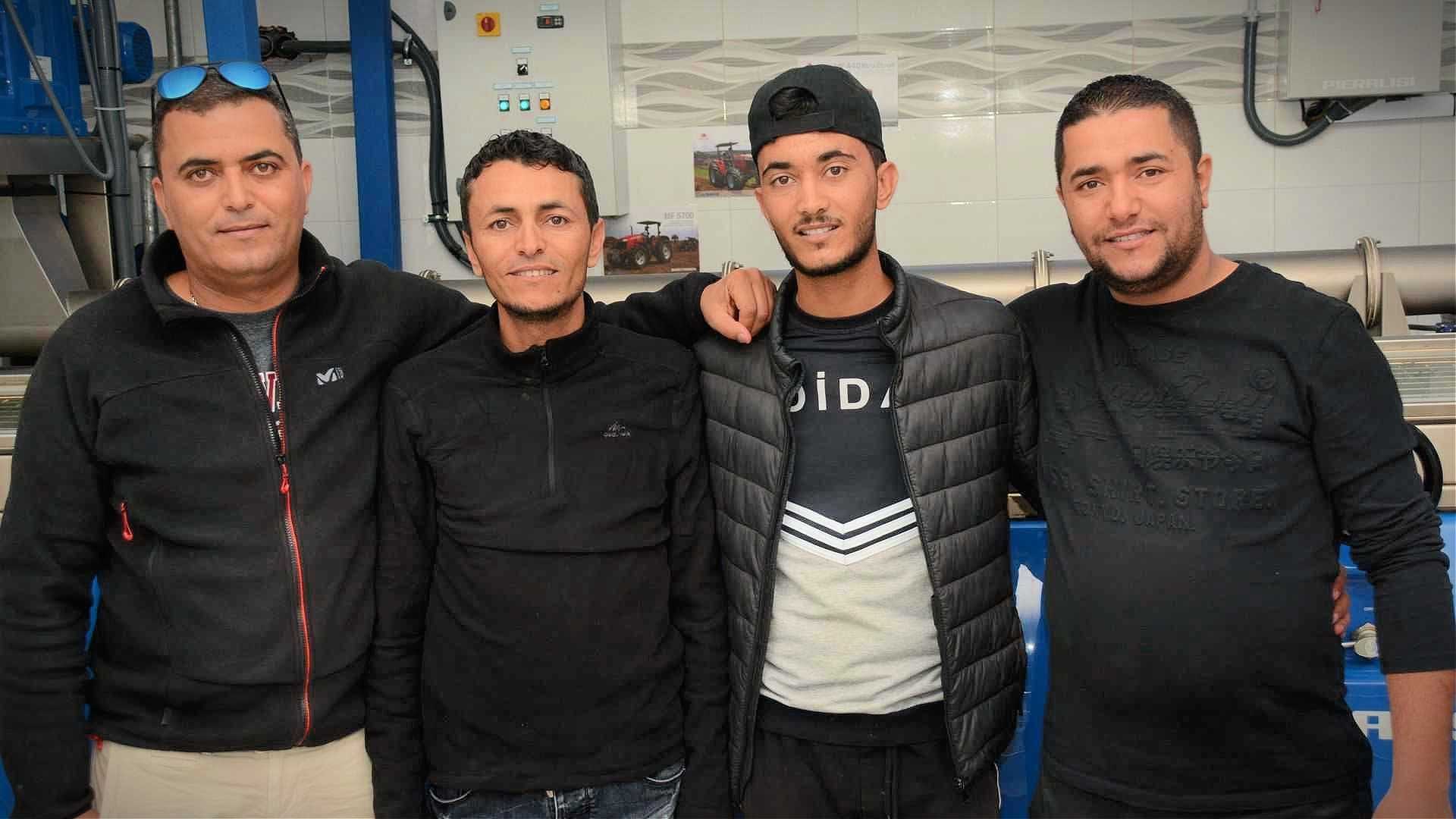 Four men wearing black clothing posing together in a casual setting. - Olive Oil Times