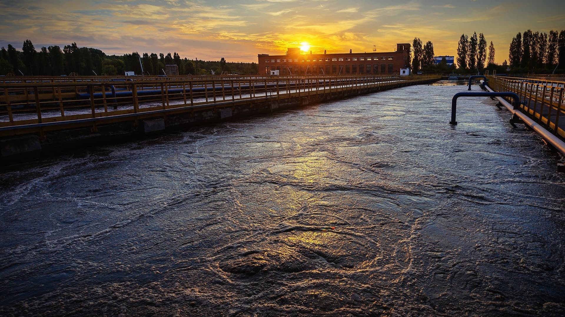 Water treatment facility with a view of the sunset reflecting on the water surface. - Olive Oil Times