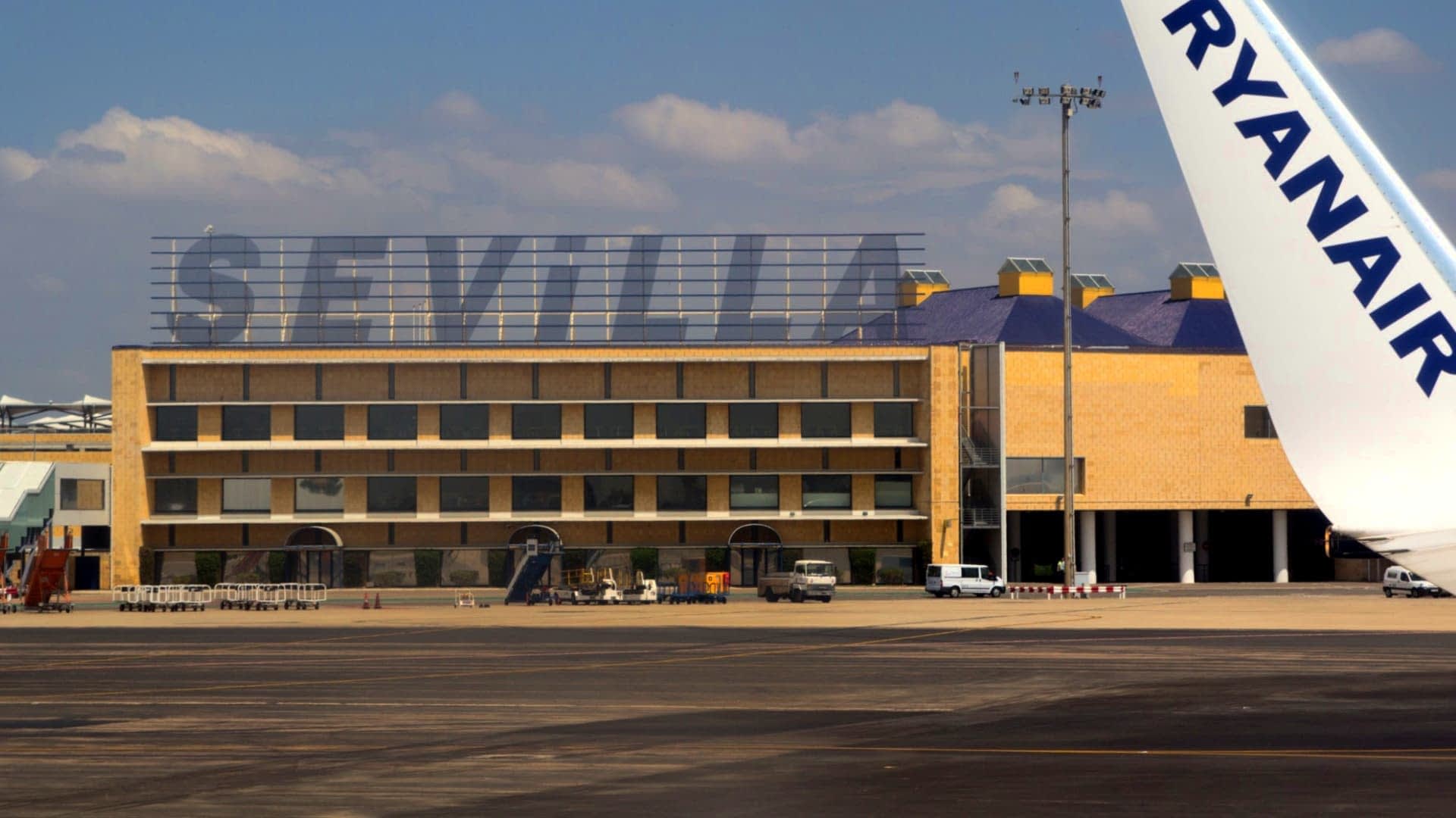 Sevilla airport building with the word 'SEVILLA' displayed prominently and a Ryanair airplane wing in the foreground. - Olive Oil Times