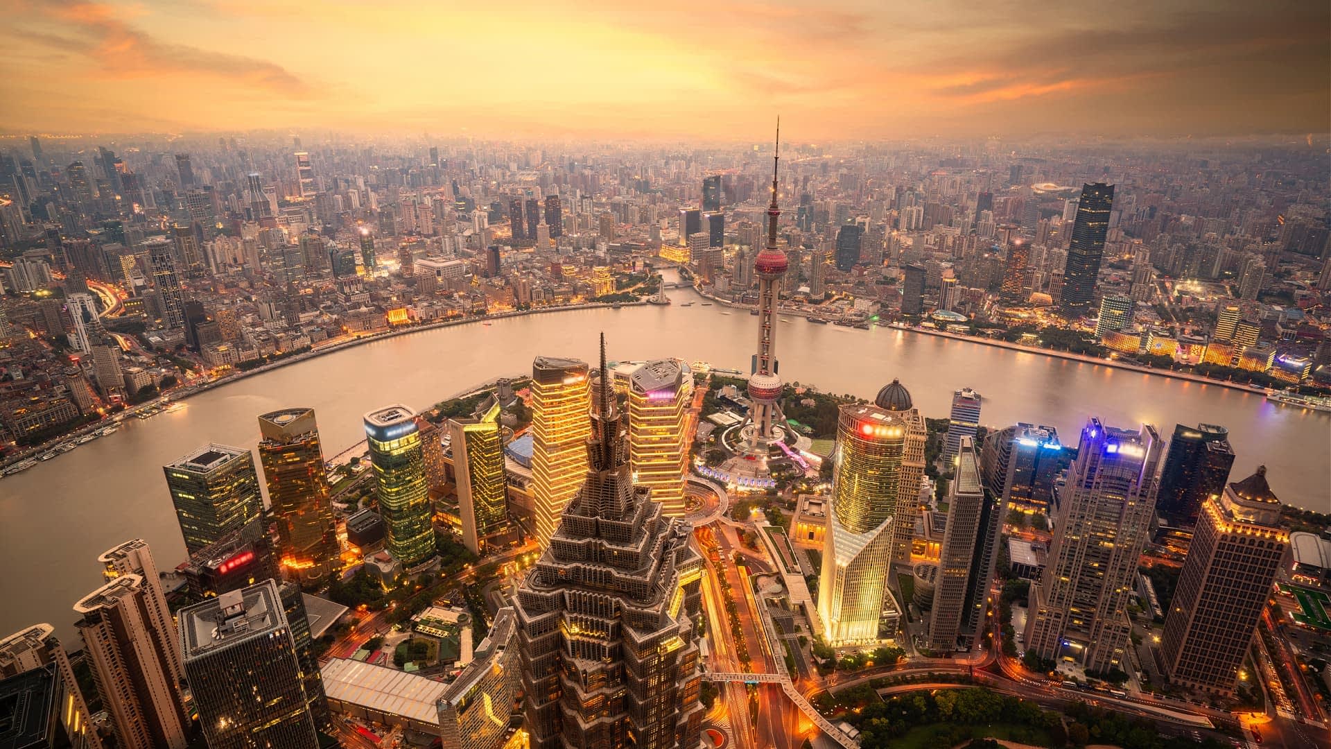 Aerial view of Shanghai's skyline featuring skyscrapers and the Huangpu River during sunset. - Olive Oil Times