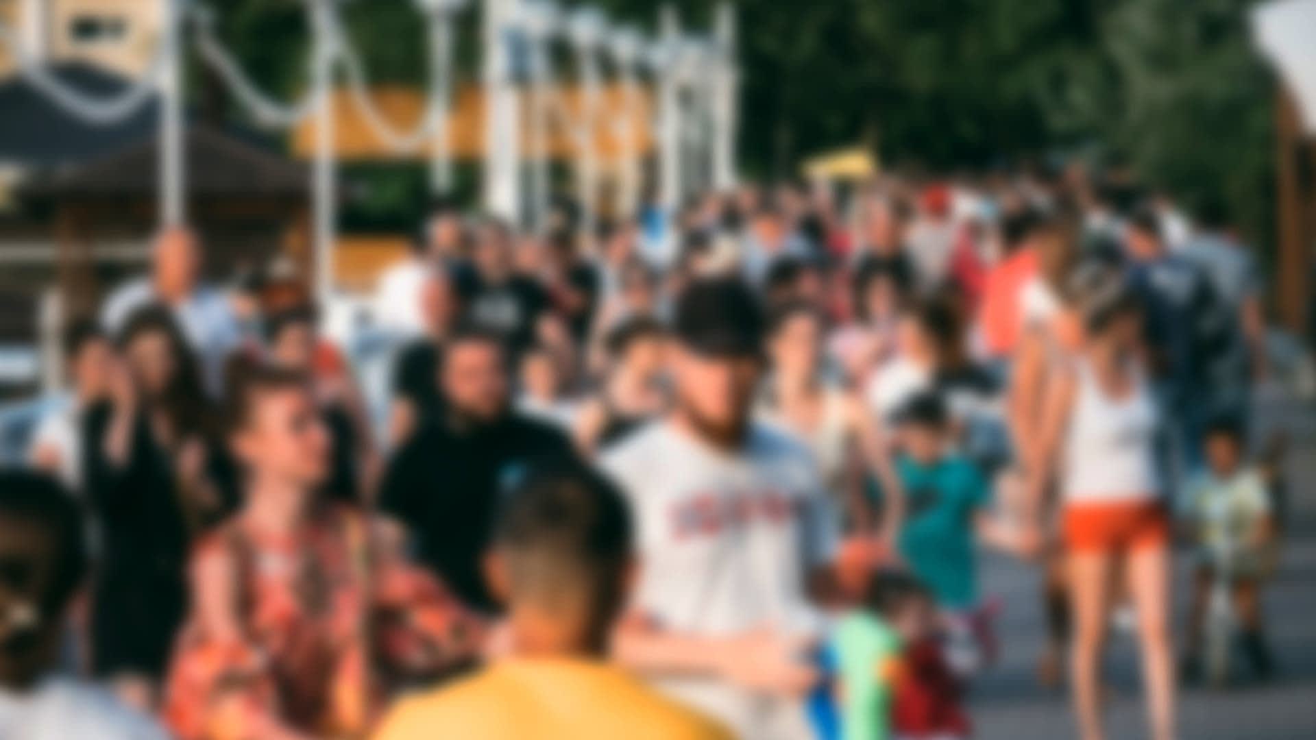 A large group of people walking together in a public area, blurred image showing diverse individuals. - Olive Oil Times