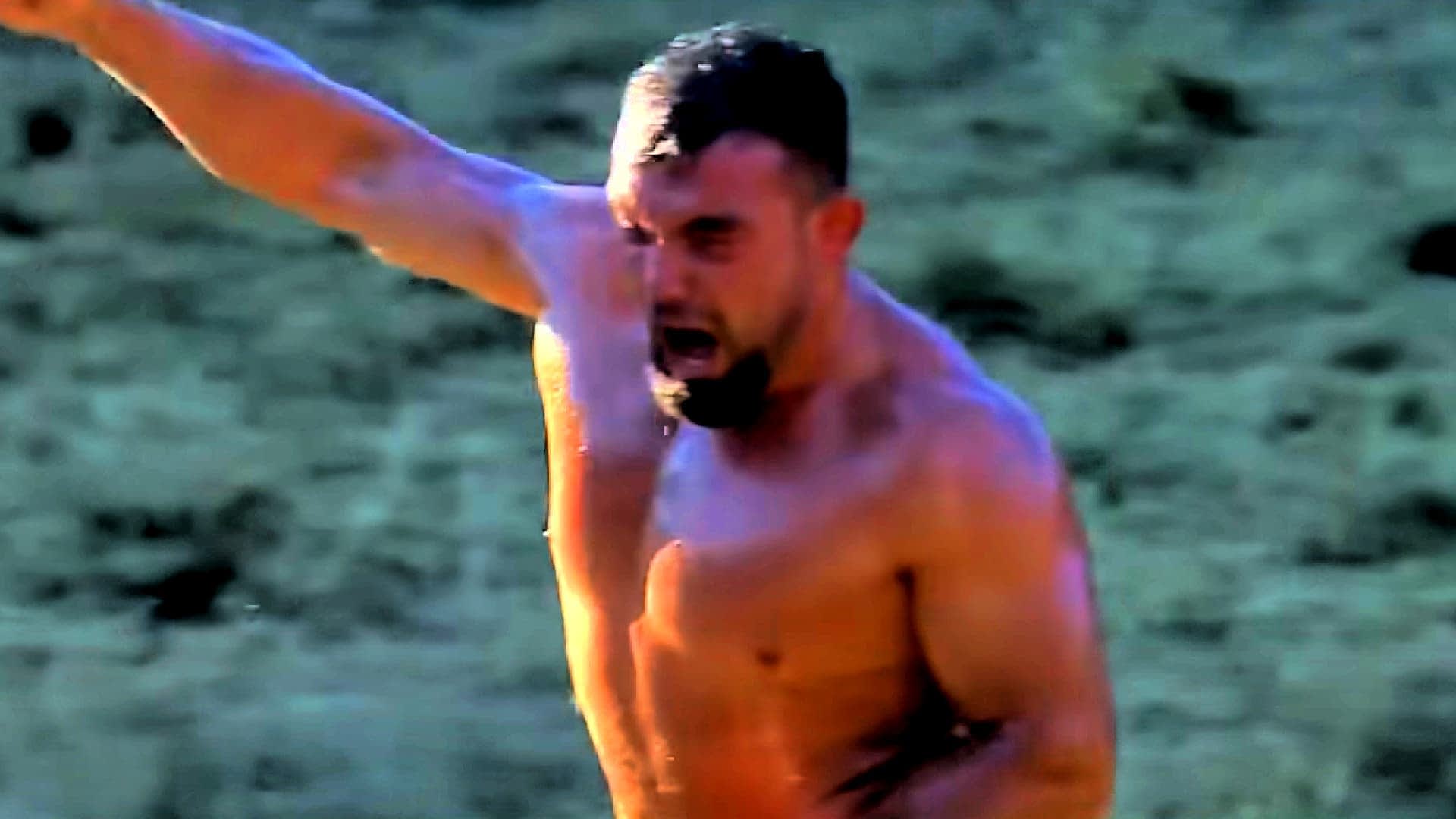 A shirtless man with a muscular build raising his arm in celebration outdoors. - Olive Oil Times