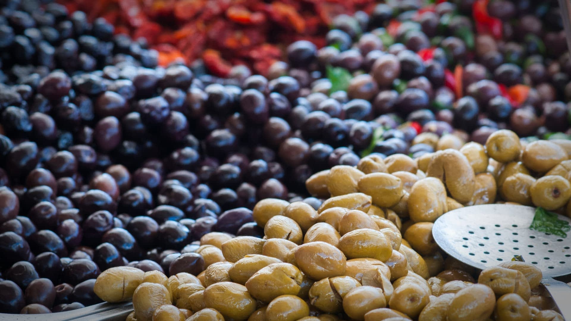 A display of green and black olives arranged in a market setting. - Olive Oil Times