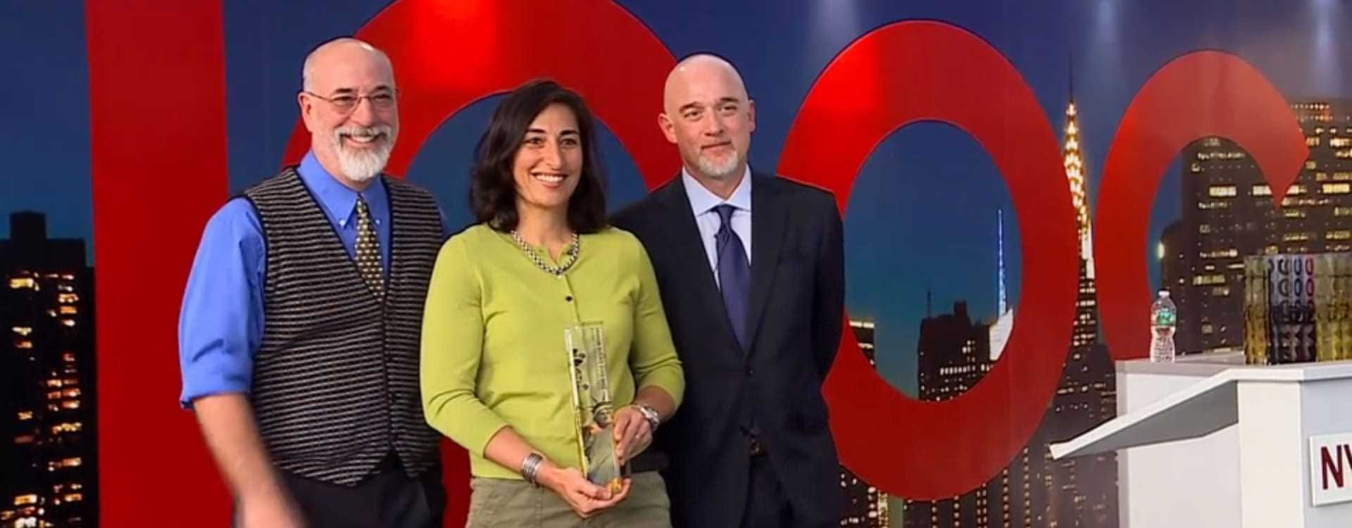 Three individuals at an award ceremony, one holding a trophy and smiling. - Olive Oil Times