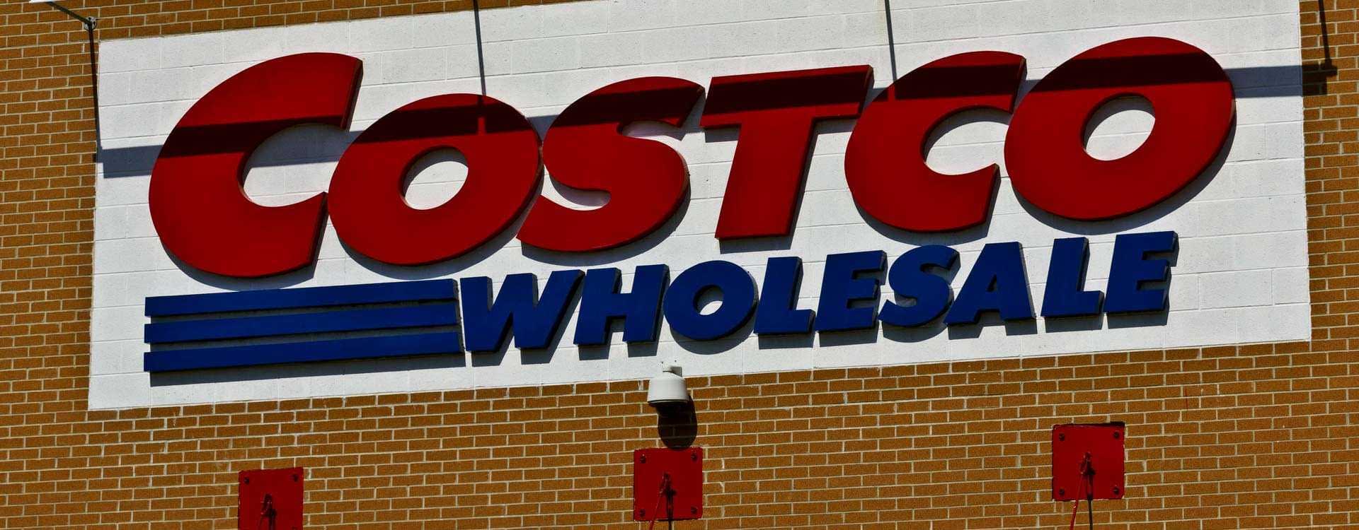 Sign displaying the Costco Wholesale logo on a brick wall. - Olive Oil Times