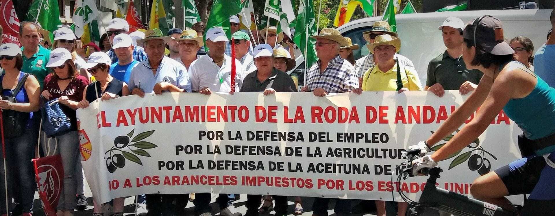 Group of protesters holding a large banner advocating for agricultural employment and olive oil support. - Olive Oil Times