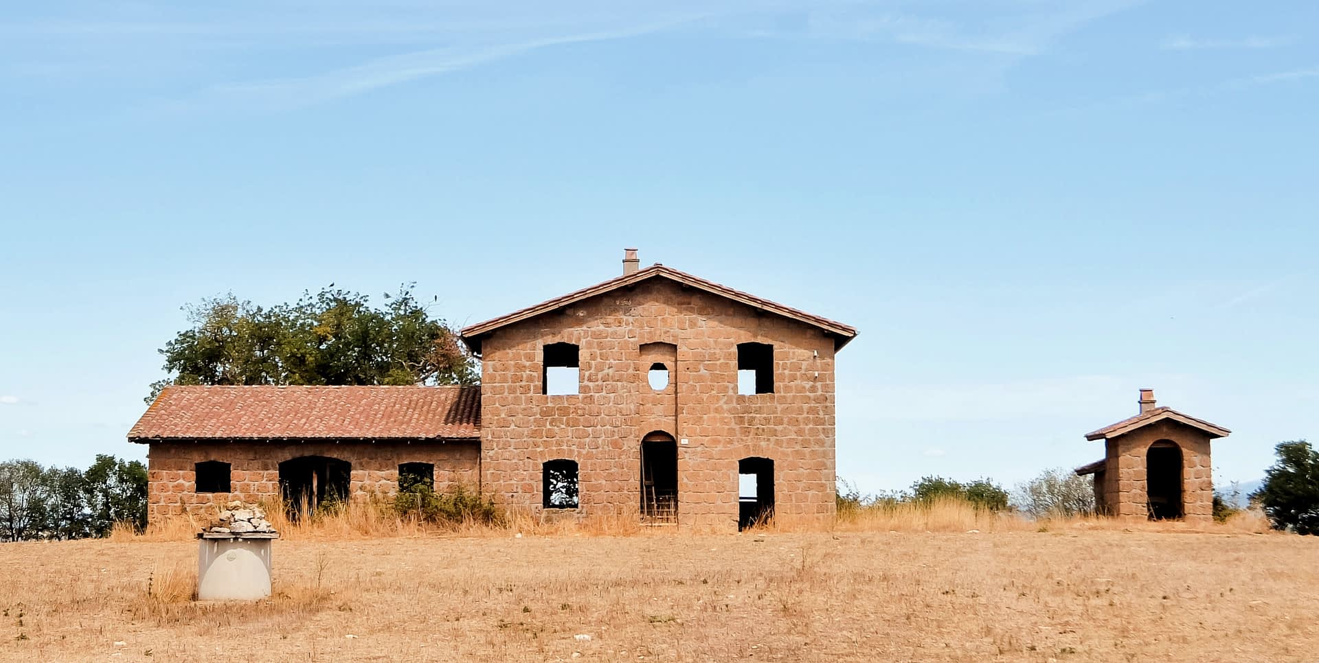 Abandoned stone building with multiple windows and a roof, set against a clear sky. - Olive Oil Times