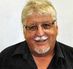 A smiling man with light hair and glasses wearing a black shirt with vertical stripes. - Olive Oil Times