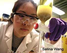 A person in a laboratory setting measuring liquid from a container into a graduated cylinder. - Olive Oil Times