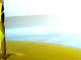 Olive oil being poured from a container into a pool of oil on a surface. - Olive Oil Times