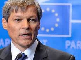 Dacian Ciolos speaking during a press conference in front of a blue backdrop with the European Union flag. - Olive Oil Times