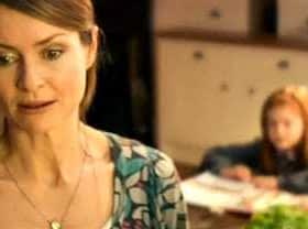 A woman with brown hair wearing a patterned top, looking thoughtfully while a child is seated in the background. - Olive Oil Times