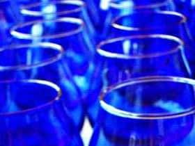 Una collezione di bicchieri blu disposti in fila, che ne mettono in risalto i colori vivaci e le forme. Olive Oil Times