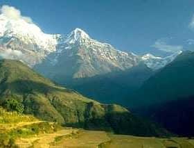 Snow-capped mountains in Nepal with clear blue sky and green hills in the foreground. - Olive Oil Times