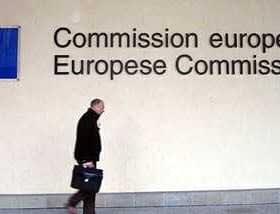 A person walking past the European Commission signage with the EU flag displayed on the wall. - Olive Oil Times
