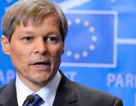 A man in a suit speaking at a press conference with a European Parliament backdrop. - Olive Oil Times