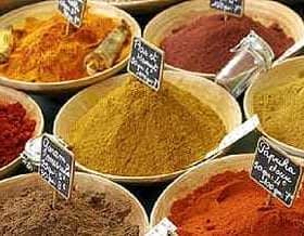 Bowls filled with various spices, each labeled with a small black sign for identification. - Olive Oil Times