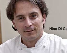 Portret van chef-kok Nino Di Costanzo, gekleed in een witte koksjas en recht in de camera kijkend. Olive Oil Times