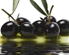 A cluster of black olives resting in olive oil with a reflective surface. - Olive Oil Times