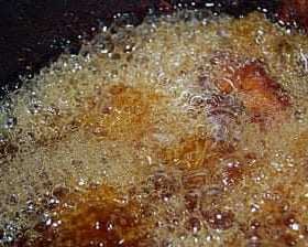 Bubbling oil in a pot during the deep frying process with food submerged. - Olive Oil Times