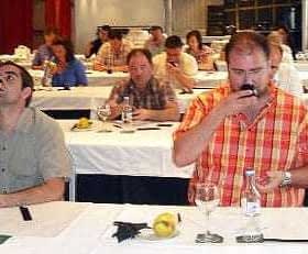 Participants at an olive oil tasting event seated at tables with glasses and bottles. - Olive Oil Times