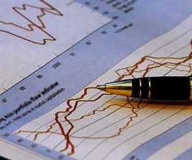 A pen resting on a sheet of paper with financial graphs and data trends. - Olive Oil Times