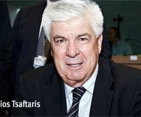 Athanassios Tsafaris seated at a table, wearing a black suit and tie, with a neutral expression. - Olive Oil Times
