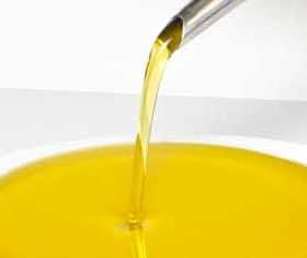 Stream of olive oil being poured from a spout into a white bowl. - Olive Oil Times