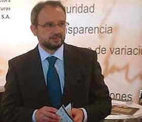 Man wearing glasses and a suit holding a document at a conference or event. - Olive Oil Times