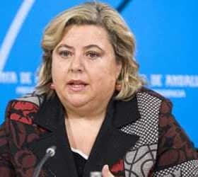 Woman with blonde hair speaking at a press conference in front of a blue backdrop. - Olive Oil Times