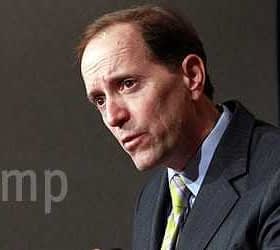 Man in a suit speaking during a press conference with a serious expression. - Olive Oil Times